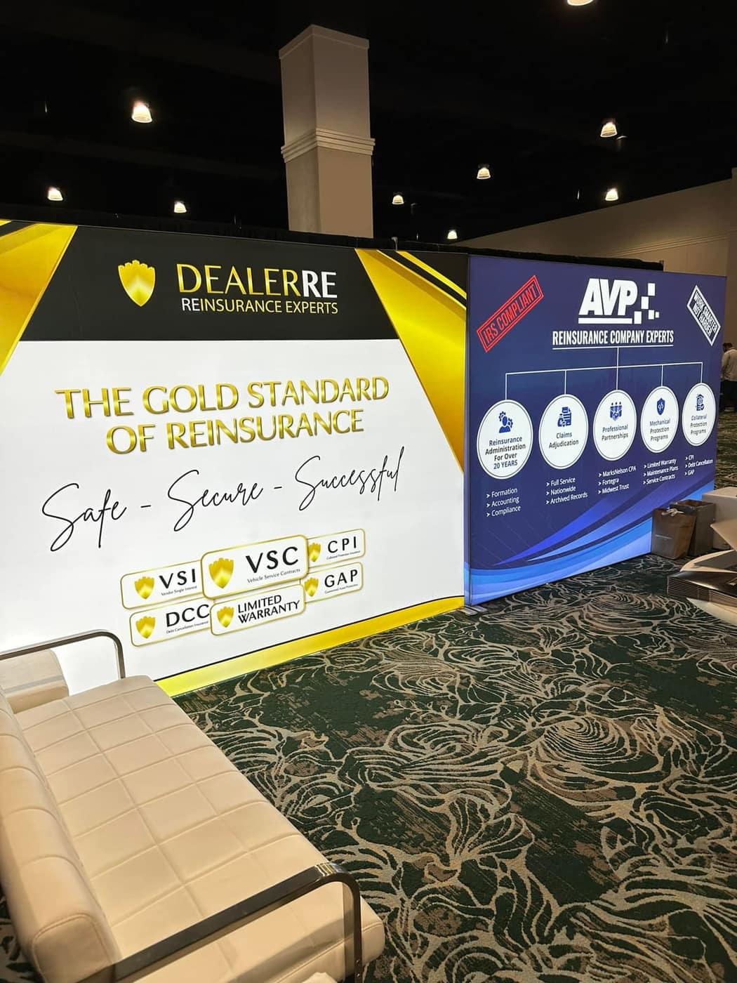 Dealerre wall in white and gold headed The gold standard of reinsurance, next to the blue AVP wall, at a show